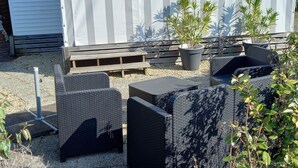 Ein Wohnmobil mit Gartenmöbeln, darunter Korbsessel und eine Bank, sowie Blumentöpfen.