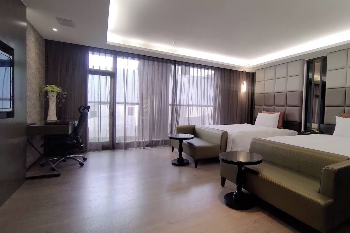 Une chambre d’hôtel avec un lit, deux canapés, un bureau et une chaise.