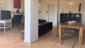 A spacious living area with a fireplace, a dining table, and a sofa. - Villa Marguerite à Arès, Près du Bassin D'arcachon et de L'ocean (Arès)