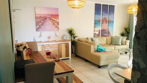 A living room with a sofa, dining table, and chairs. There are wall art pieces and a lamp. - The blyde 3 bedroom crystal Lagoon beach  (Pretoria)