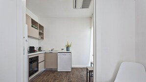 Cocina compacta con lavavajillas, cafetera y una planta en maceta sobre la encimera.