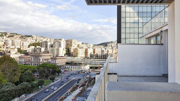 Un edificio moderno con vistas a una calle urbana concurrida y edificios históricos al fondo.