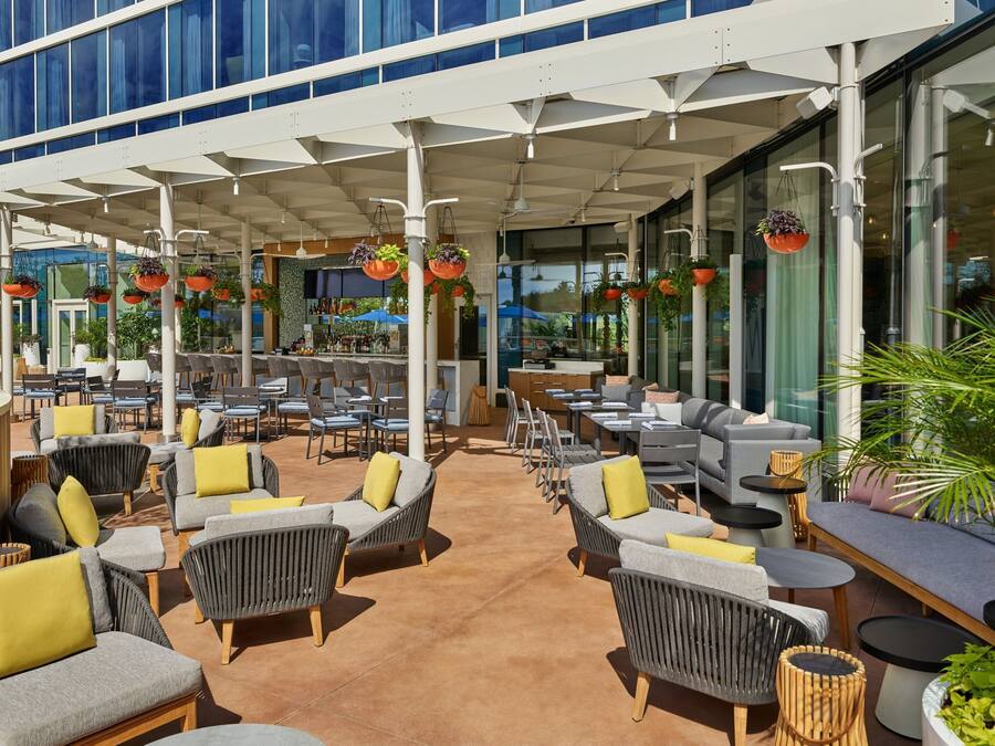 An outdoor seating area with wicker furniture, yellow cushions, and hanging planters.