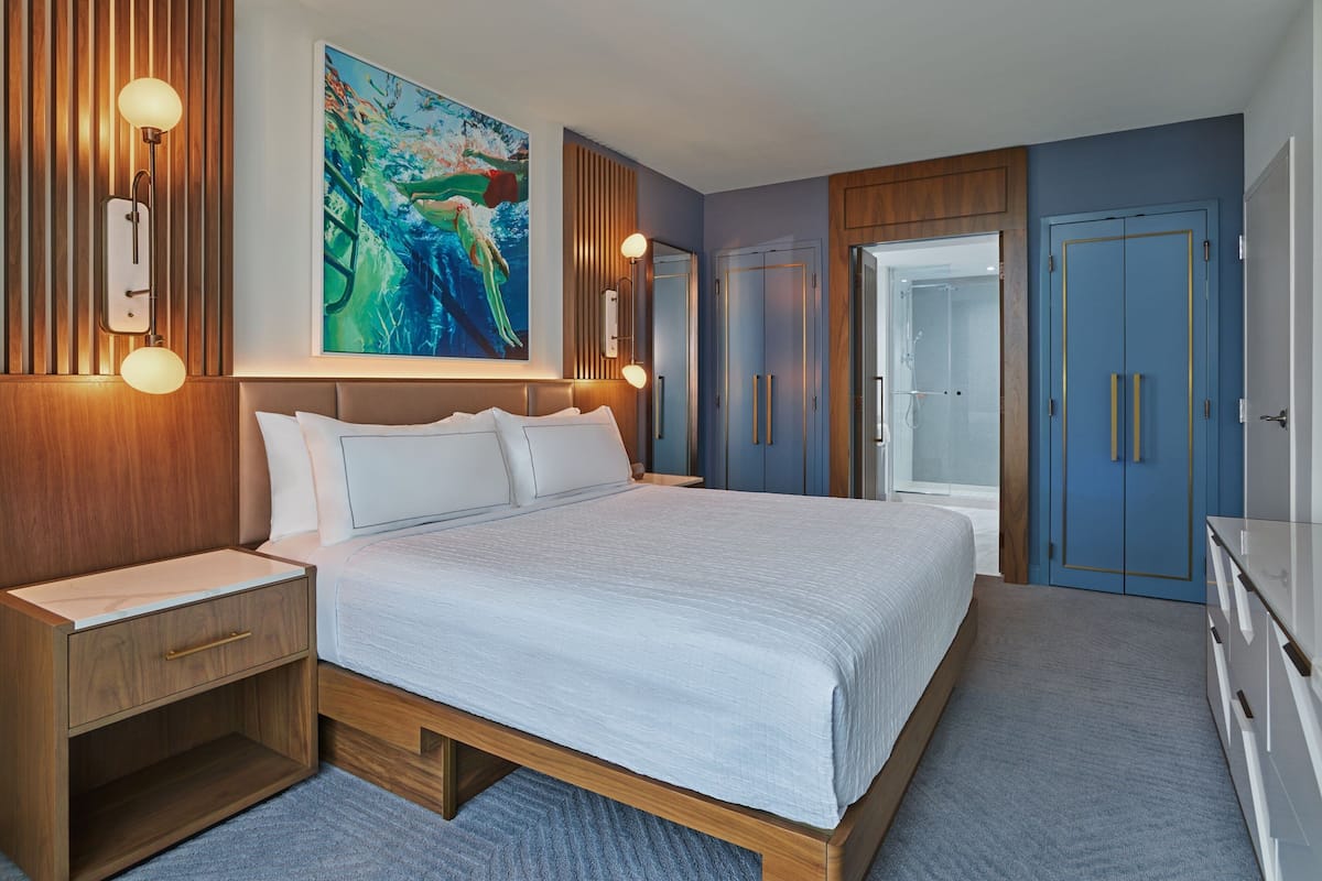 Een moderne slaapkamer met een groot bed, een houten hoofdeinde, nachtkastjes en een garderobe.