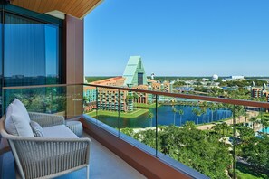 Un balcón con mobiliario de mimbre que da a una zona de resort con un edificio grande, un lago y un campo de golf.