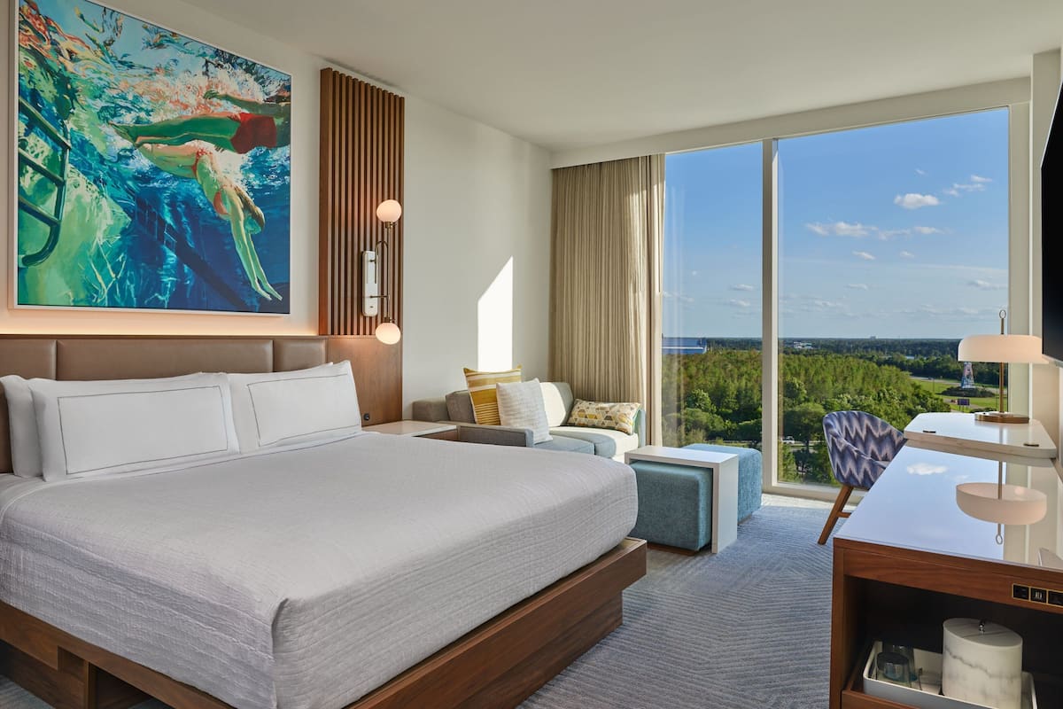 Een moderne hotelkamer met een groot bed, een bureau, een stoel en uitzicht op de omgeving.