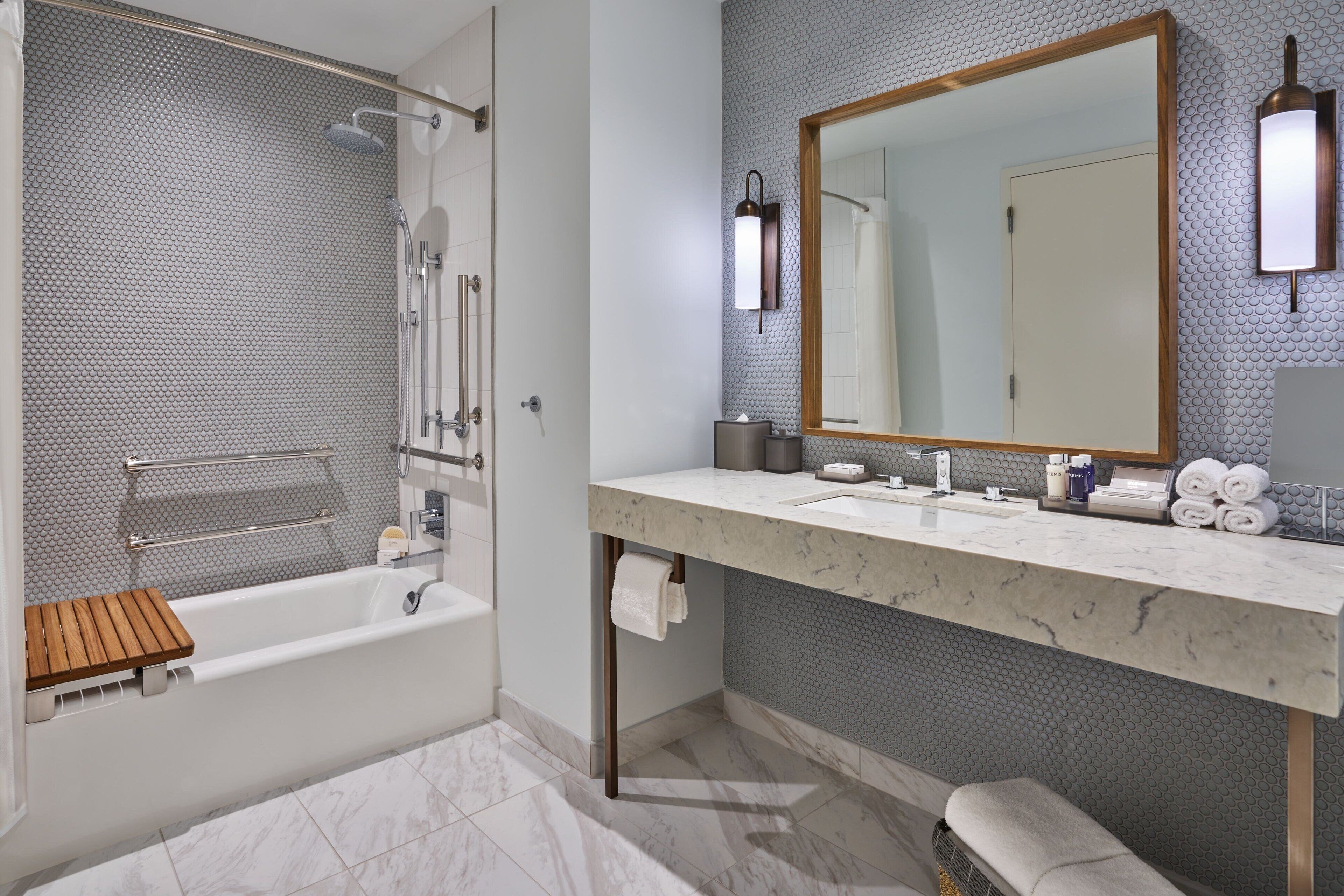 A modern bathroom with a bathtub, a large mirror, and a marble countertop.