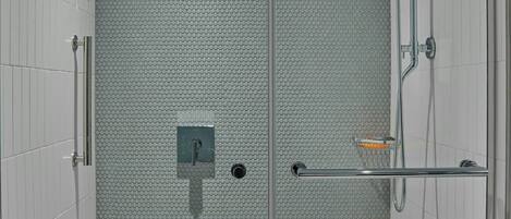Ducha moderna con puerta de vidrio, cabezal de ducha de mano y rociador de mano.