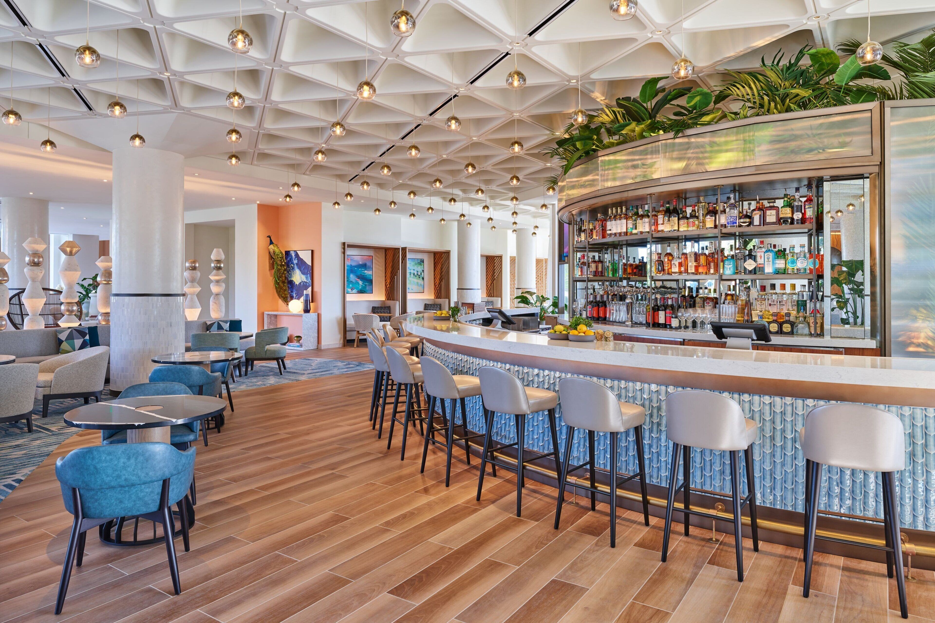 A modern bar area with a curved counter, bar stools, and a variety of liquor bottles.