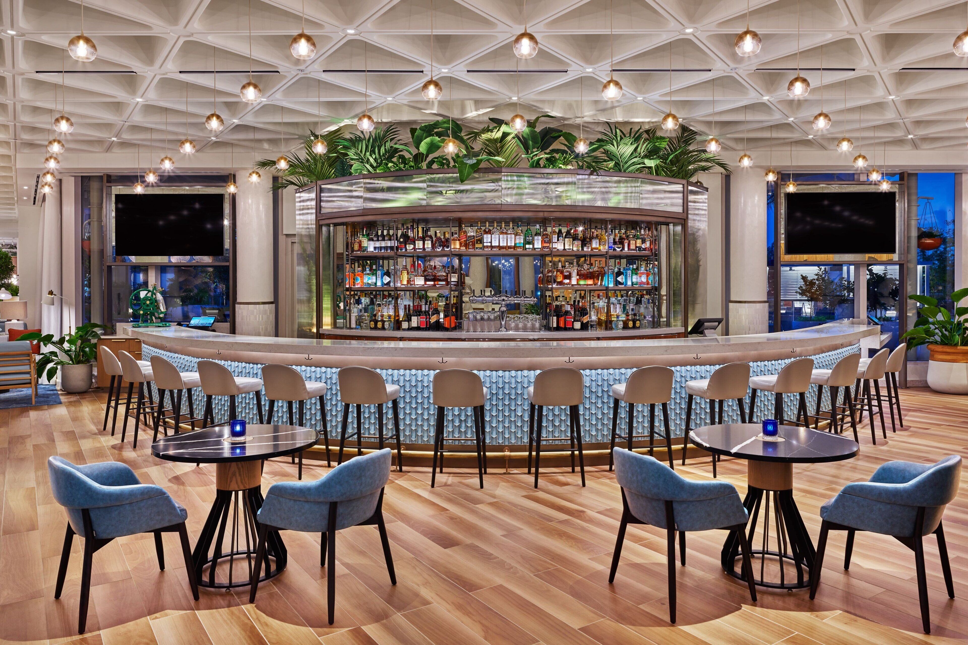 A bar area with a curved counter, multiple seating options, and a ceiling with a geometric pattern.