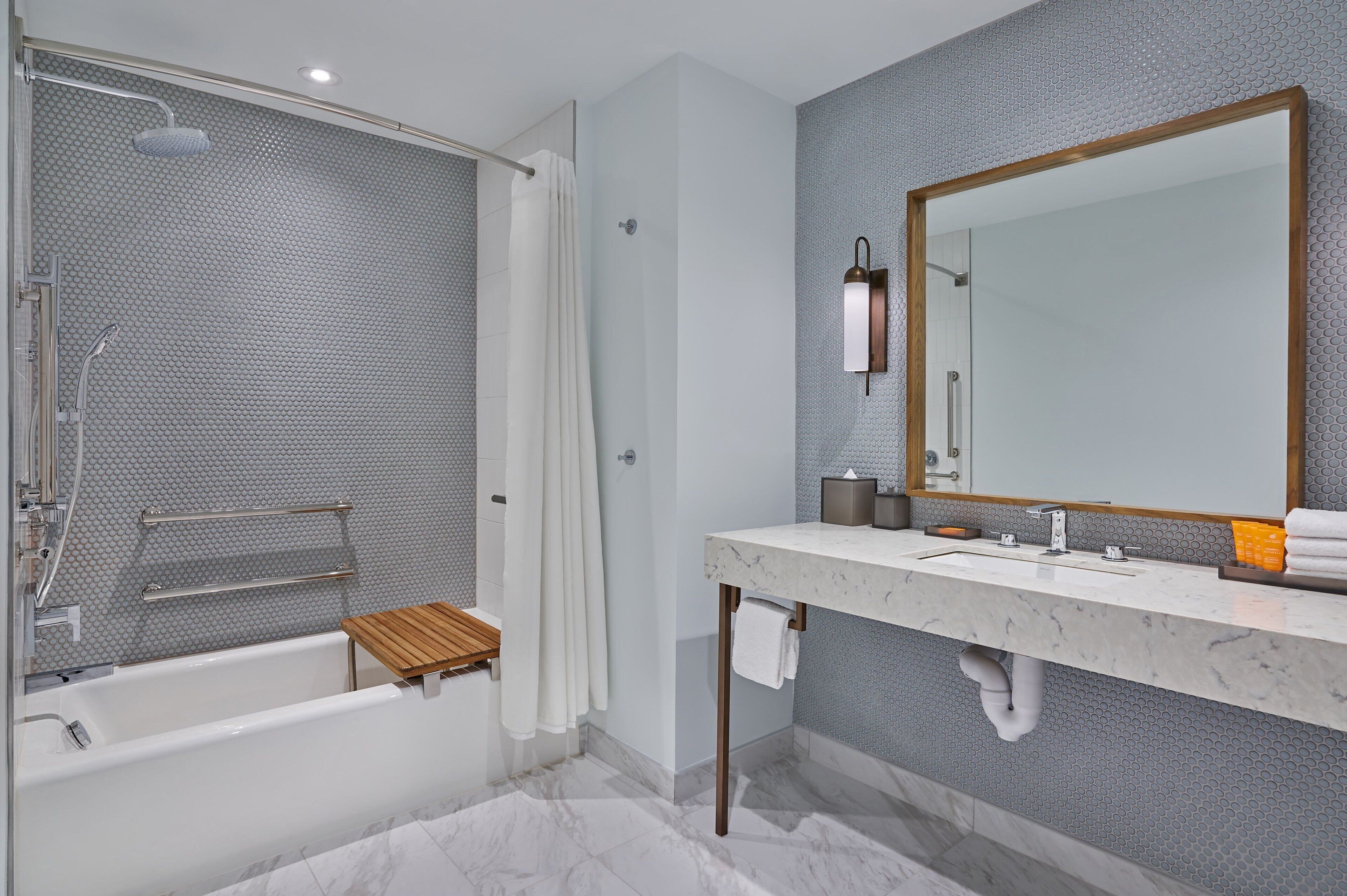 A modern bathroom with a bathtub, shower, and vanity with a large mirror.