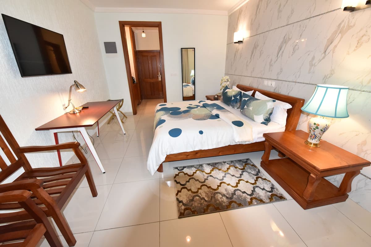 Un dormitorio con cama, mesitas de noche, un escritorio y sillas.