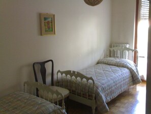 Une chambre avec deux lits, une chaise et un radiateur.
