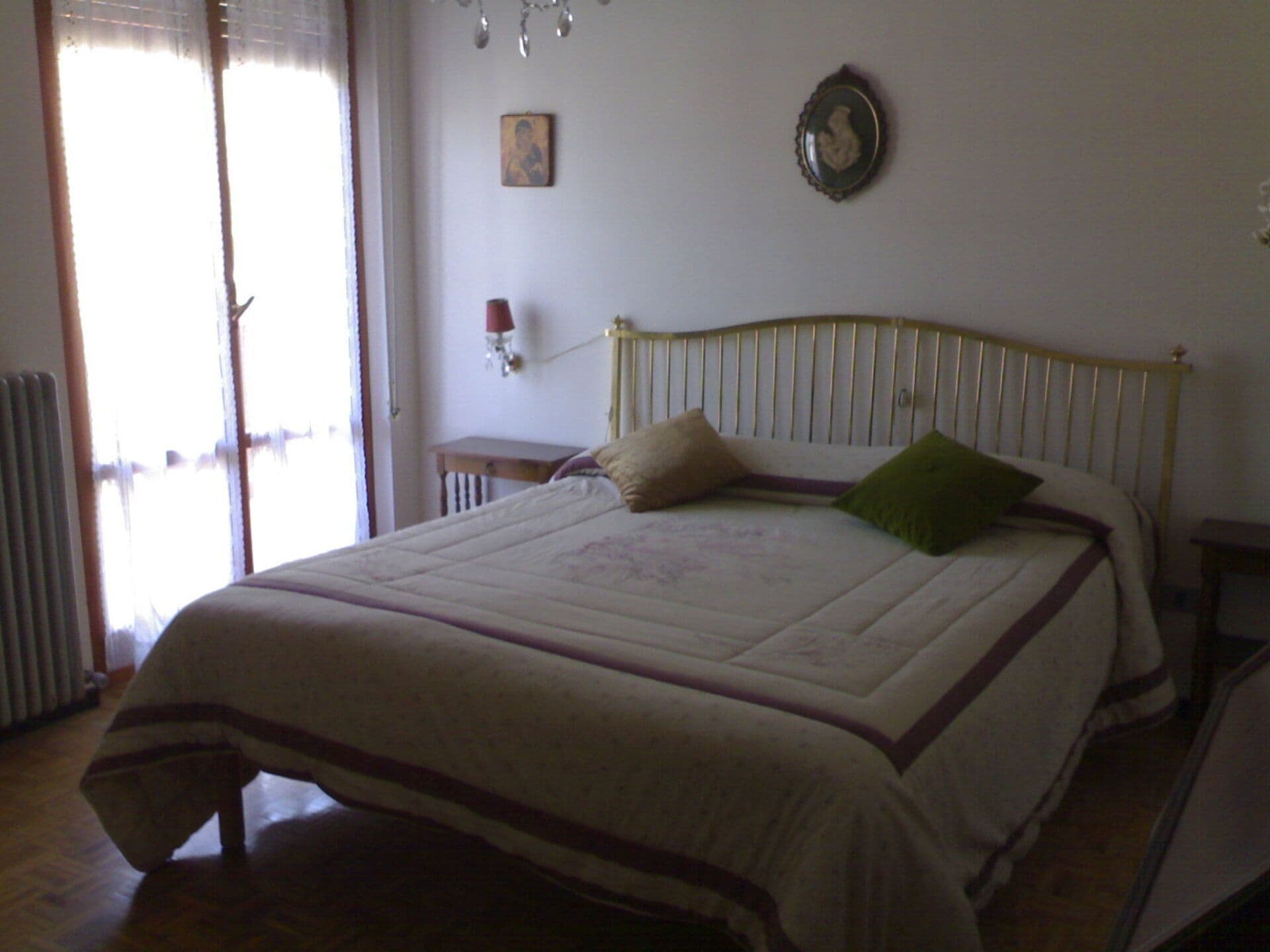 Een slaapkamer met een bed, een nachtkastje, een wandklok en een raam met gordijnen.