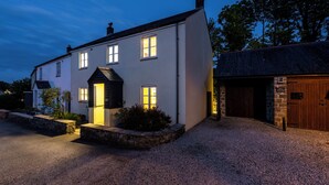 Une maison à deux étages avec une allée en gravier et un mur en pierre.