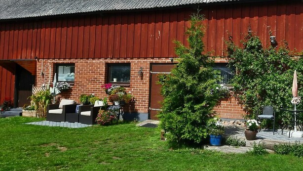 A red barn with a brick exterior, a small porch with outdoor furniture, and potted plants. - 1 Bed Flat - Sleeps 3 - Pets - Parking - Wifi (Tollarp)