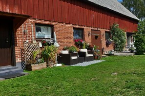 A red brick building with a sloped roof, a front door, and windows. There are potted plants and outdoor furniture in front. - 1 Bed Flat - Sleeps 3 - Pets - Parking - Wifi (Tollarp)