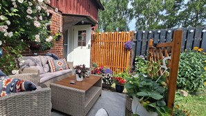 A patio with wicker furniture, a wooden table, and a variety of potted plants and flowers. - 1 Bed Flat - Sleeps 3 - Pets - Parking - Wifi (Tollarp)