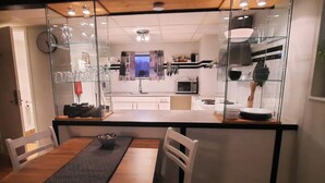 A modern kitchen with a central island, a dining area with a table and chairs, and a view through a glass partition to the living area. - 1 Bed Flat - Sleeps 3 - Pets - Parking - Wifi (Tollarp)