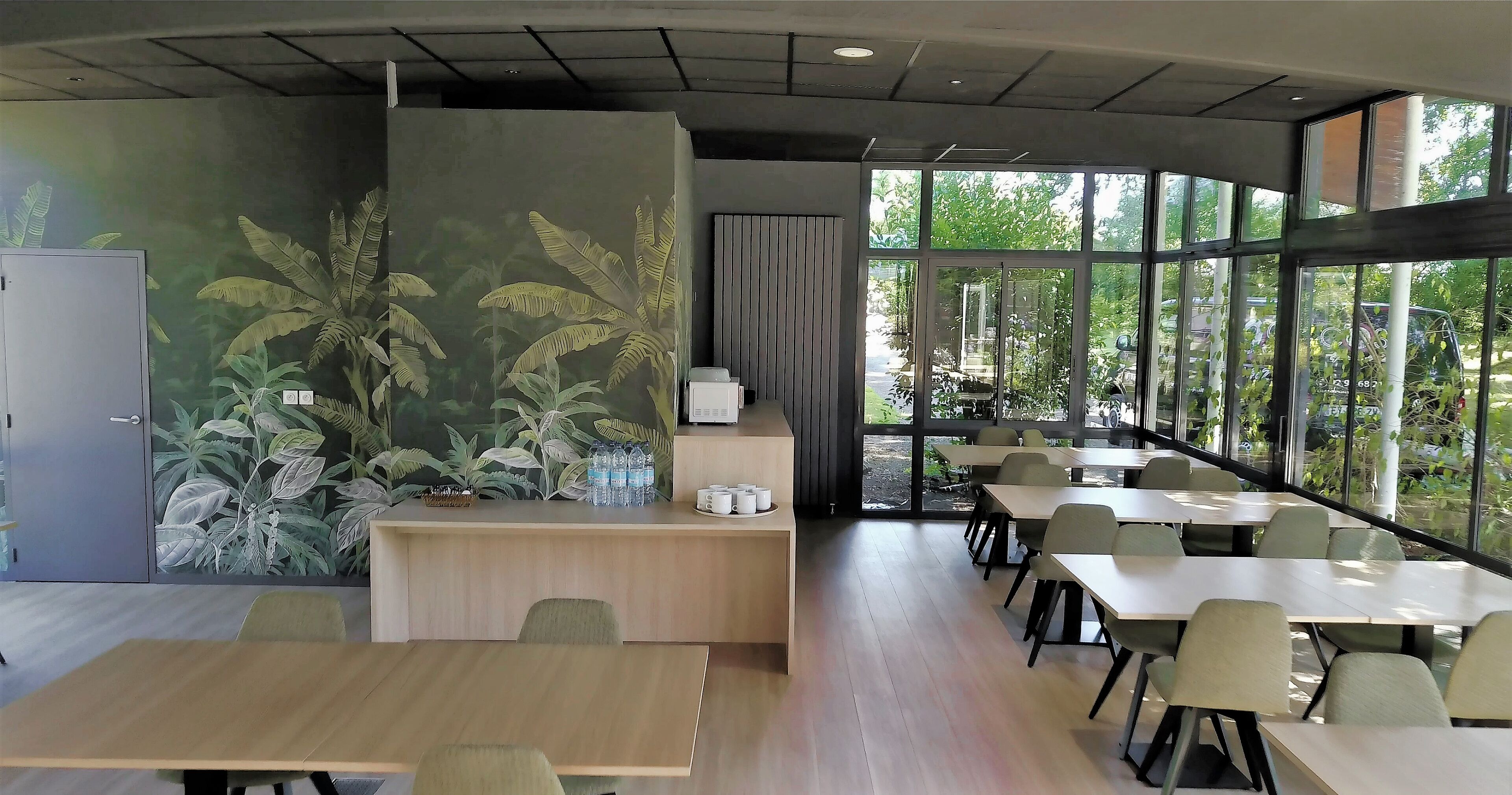 Une salle de conférence moderne dotée d’une grande fenêtre, d’un comptoir d’accueil et de plusieurs tables et chaises.