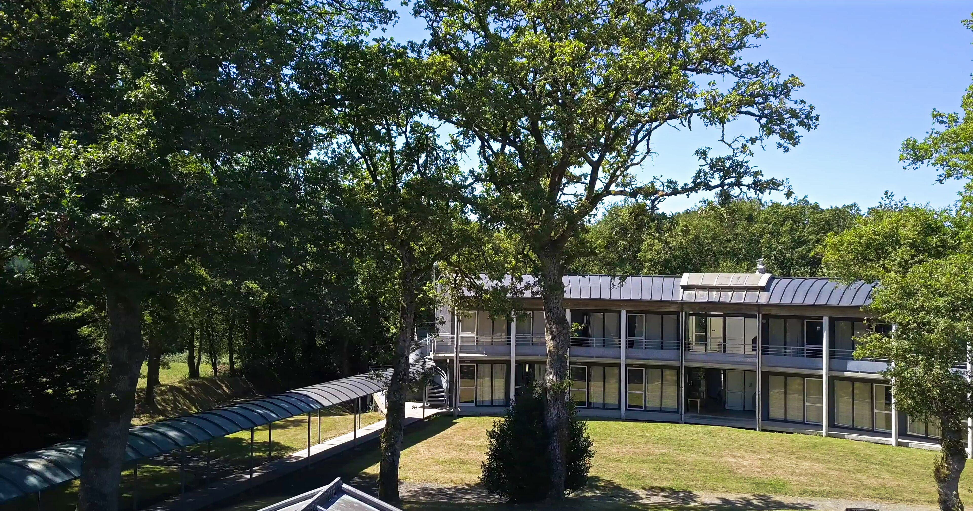 A modern building with a flat roof, large windows, and a covered walkway.