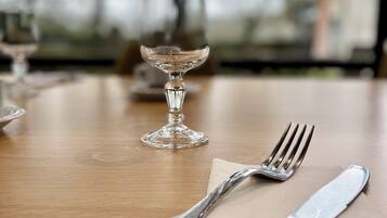 Une table à manger avec un verre à vin en verre transparent, une fourchette et un couteau.