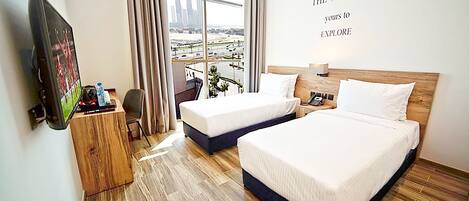 A hotel room with two beds, a TV, a desk, and a large window with a city view.
