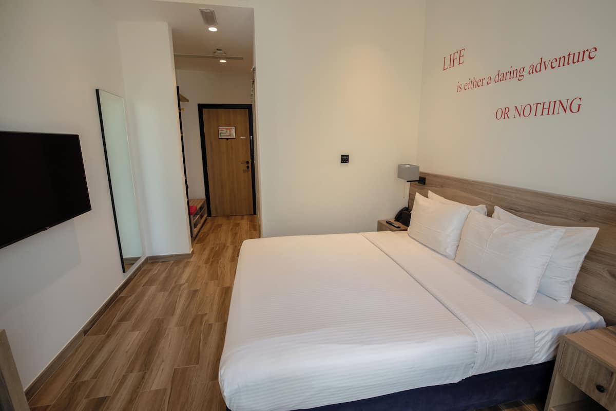Camera d'albergo con un letto grande, una TV a schermo piatto montata a parete e una frase motivazionale sulla parete.
