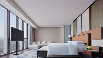 Habitación de hotel moderna con una cama grande, un sofá, un televisor de pantalla plana y vistas a la ciudad.