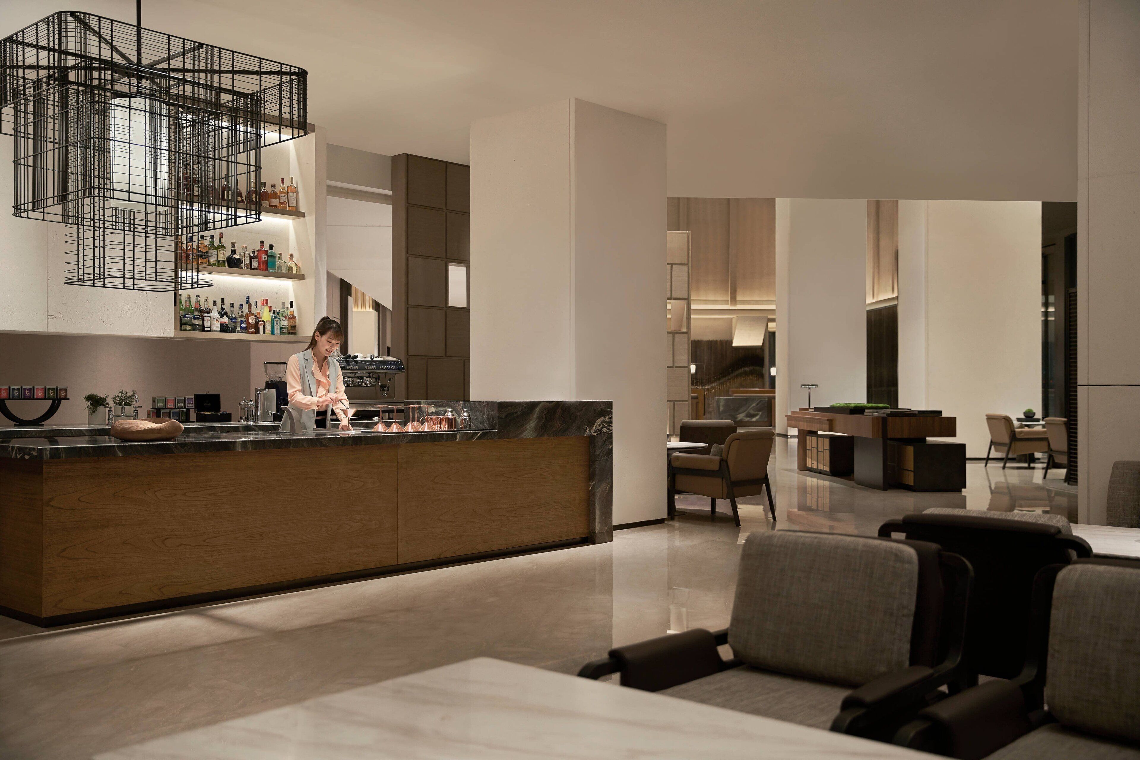 Eine moderne Hotelhalle mit Barbereich, Sitzgelegenheiten und freundlicher Beleuchtung.