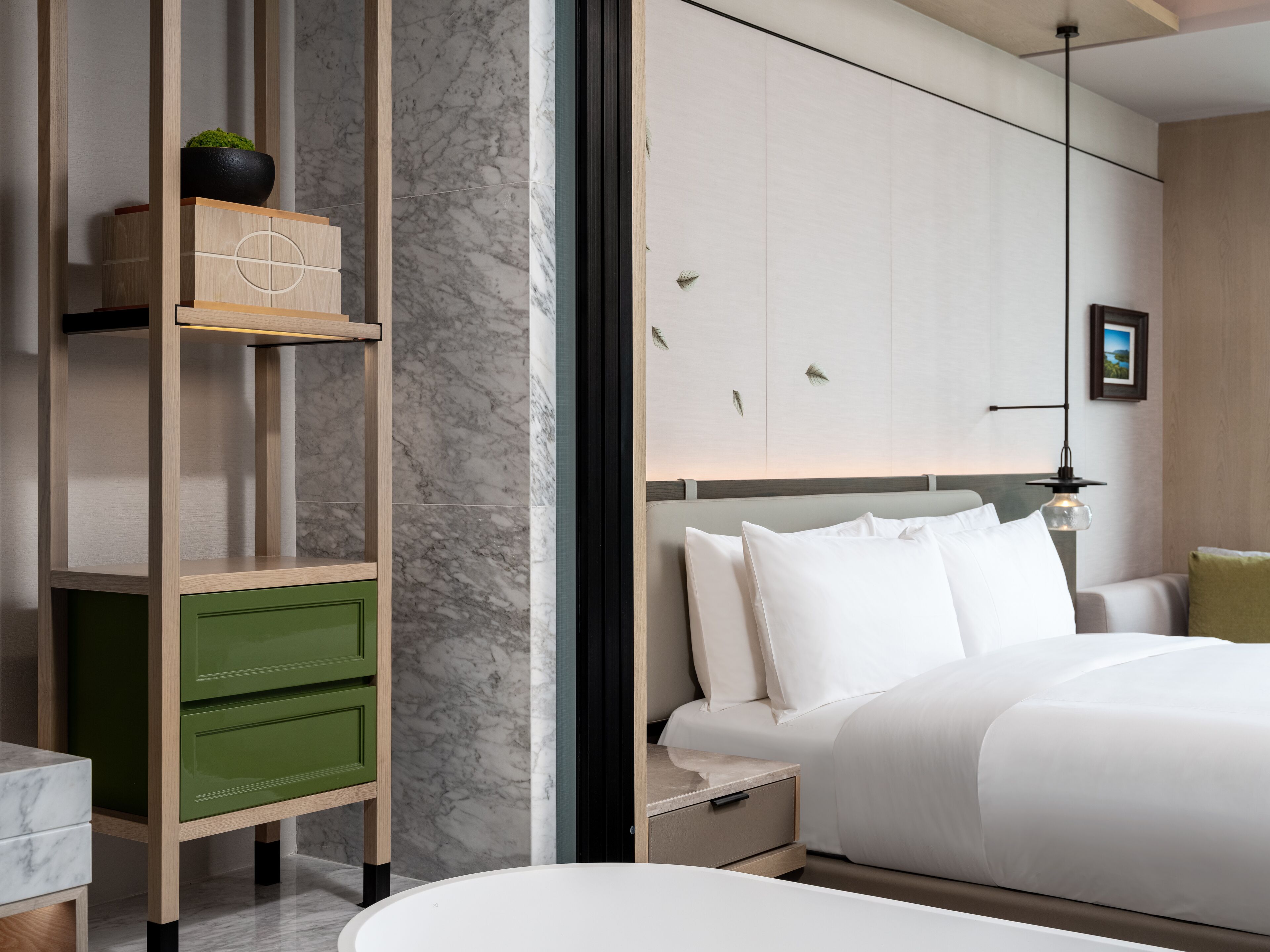 Una habitación de hotel moderna con cama, mesita de noche, un armario verde y una pared de mármol.