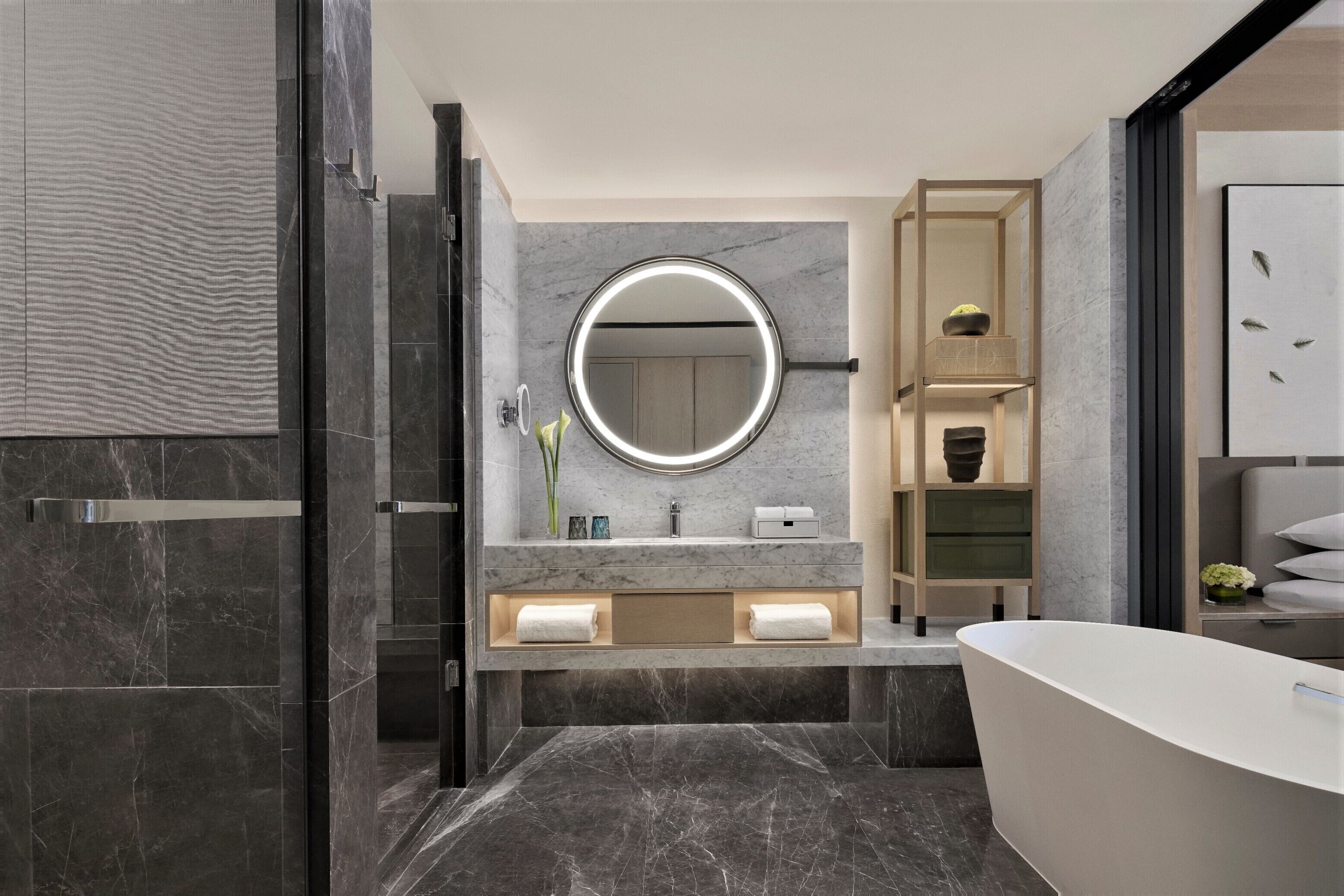 A modern bathroom with a large mirror, a freestanding bathtub, and a vanity with a marble countertop.
