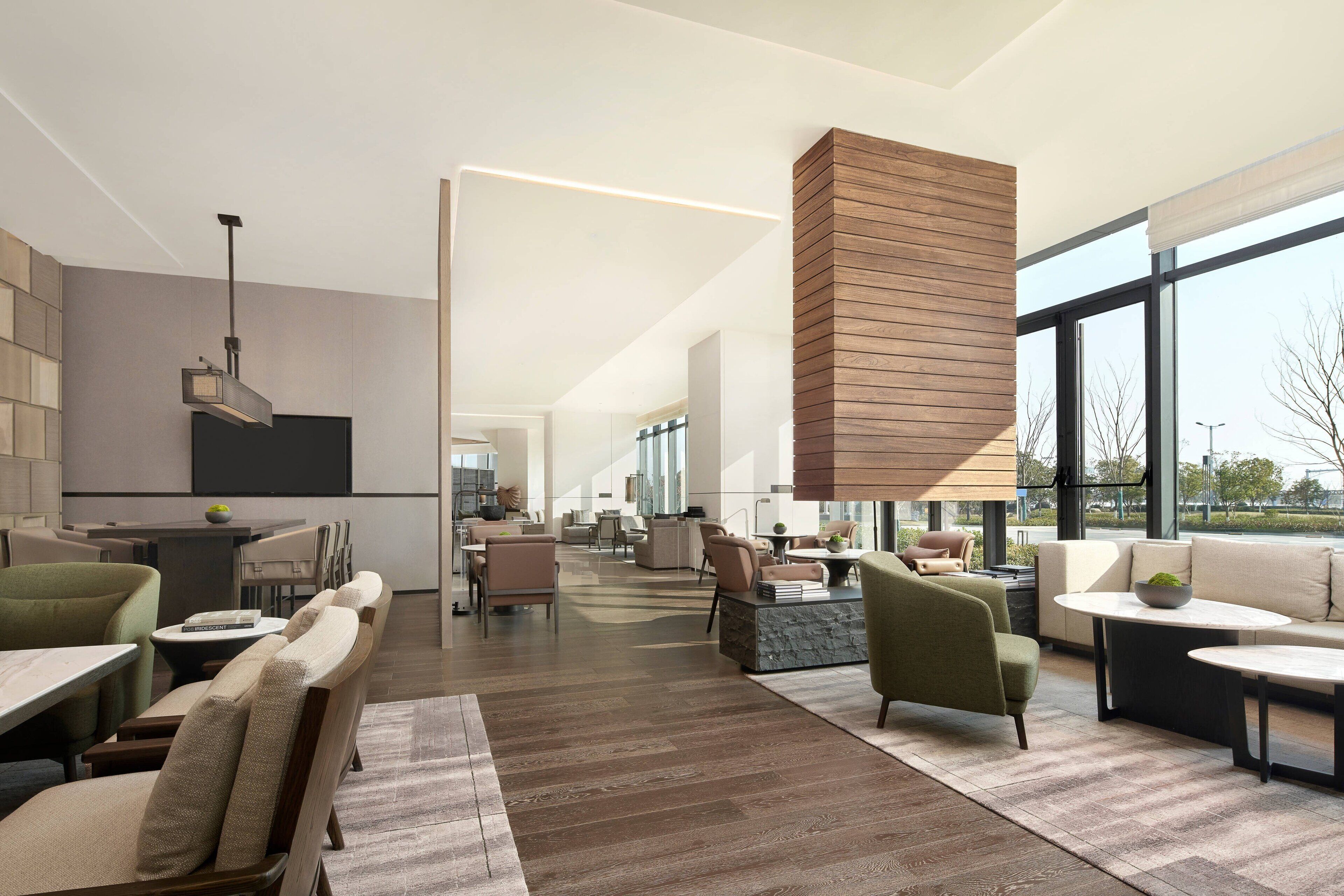 Un interior espacioso y moderno con una larga zona de comedor, asientos cómodos y grandes ventanales con vistas al exterior.