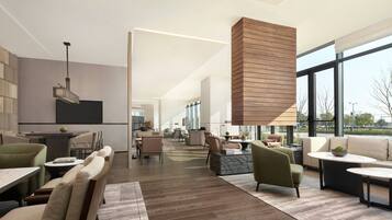 Un interior espacioso y moderno con una larga zona de comedor, asientos cómodos y grandes ventanales con vistas al exterior.