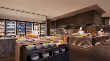 A buffet setup with various food items and a chef preparing food.
