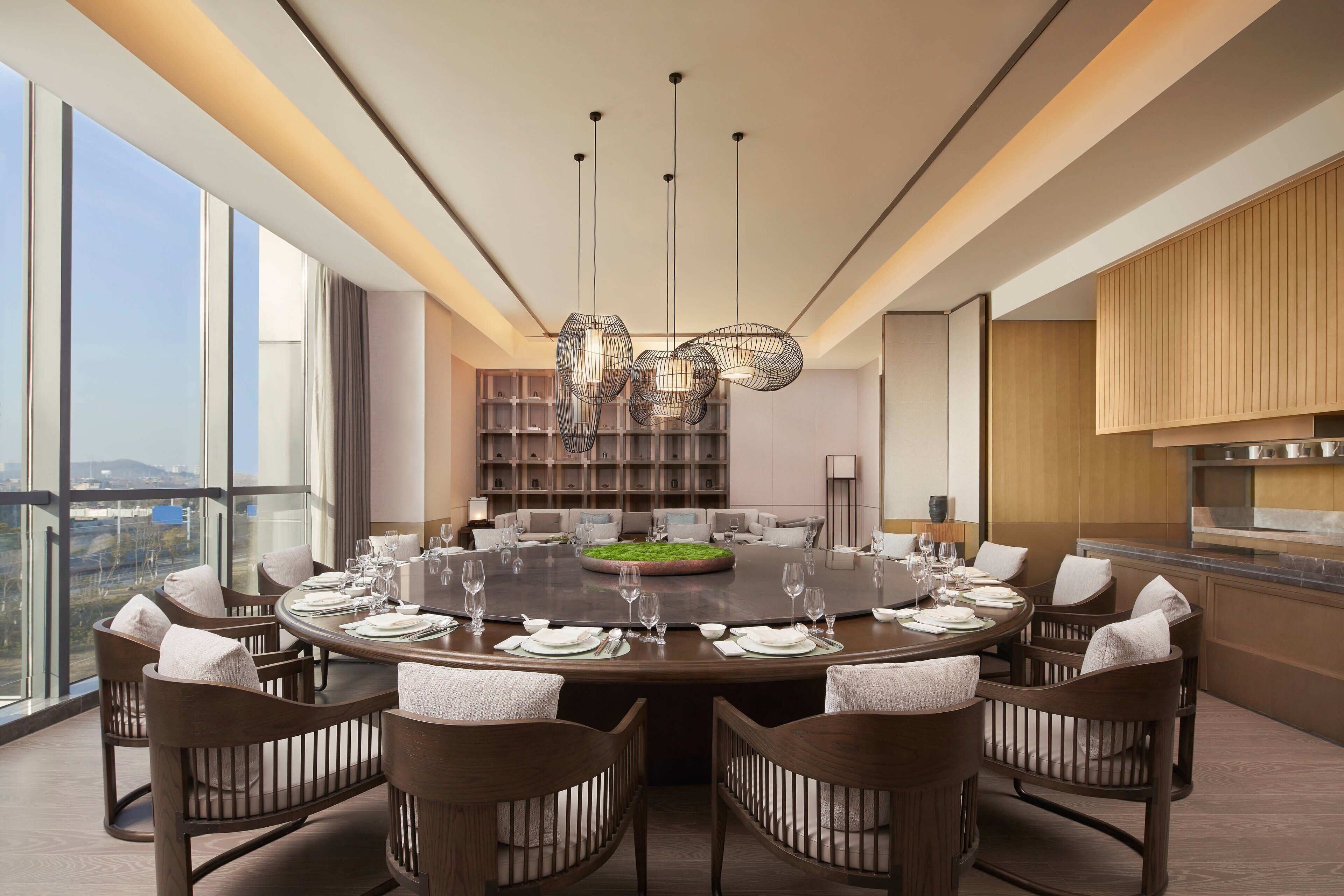 A modern dining room with a round table set for six, surrounded by wooden chairs.