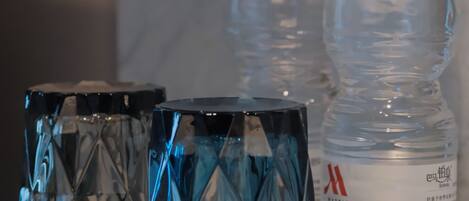 Three glass tumblers on a marble surface with two water bottles in the background.