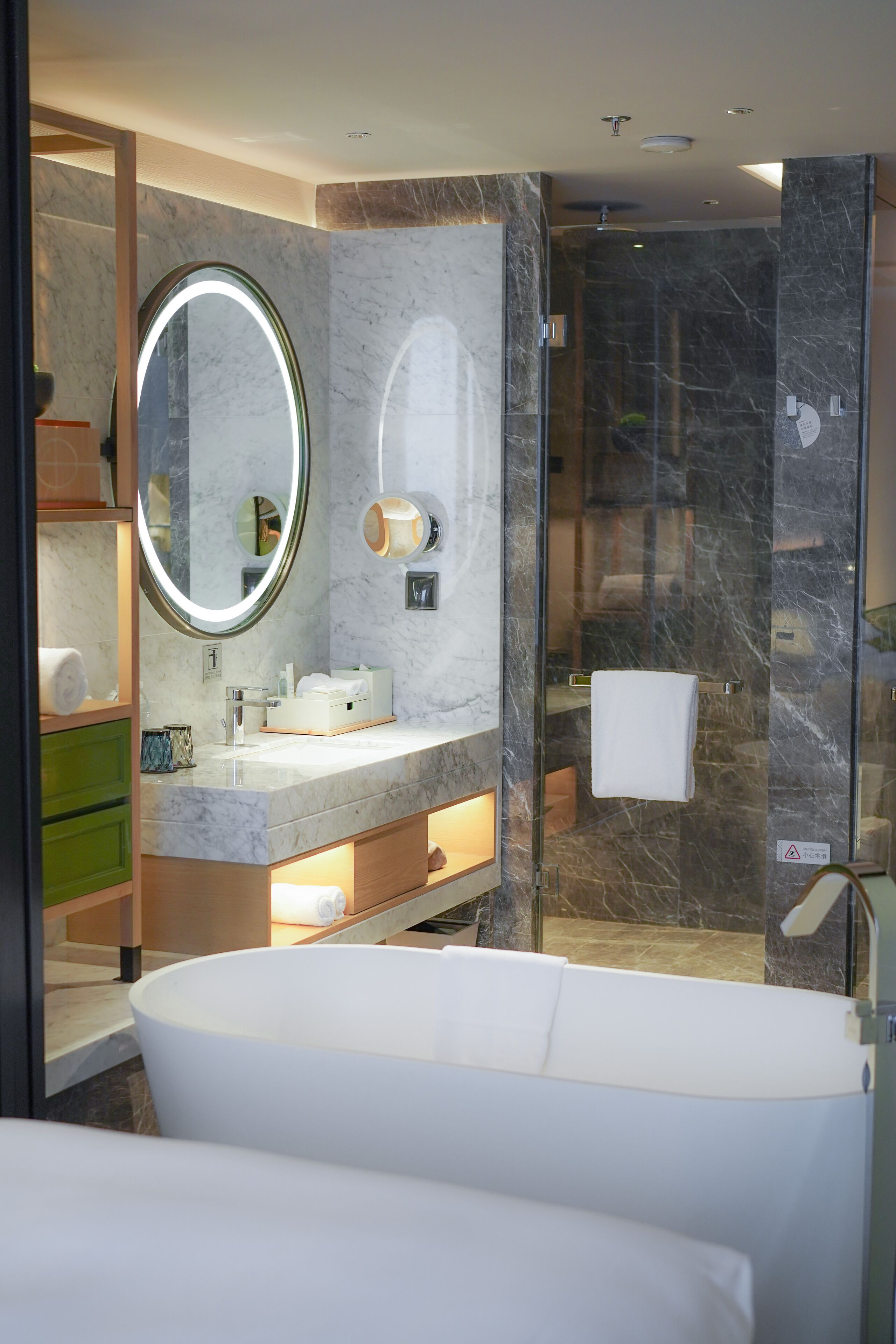 Ein modernes Badezimmer mit freistehender Badewanne, einem Waschtisch mit Spiegel und einer Duschkabine.
