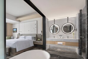 A modern bathroom with a bathtub, two round mirrors, and a vanity with a marble countertop. - Liyang Marriott Hotel (Changzhou)