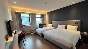 Quarto de hotel com duas camas, uma mesa, uma cadeira e uma televisão.