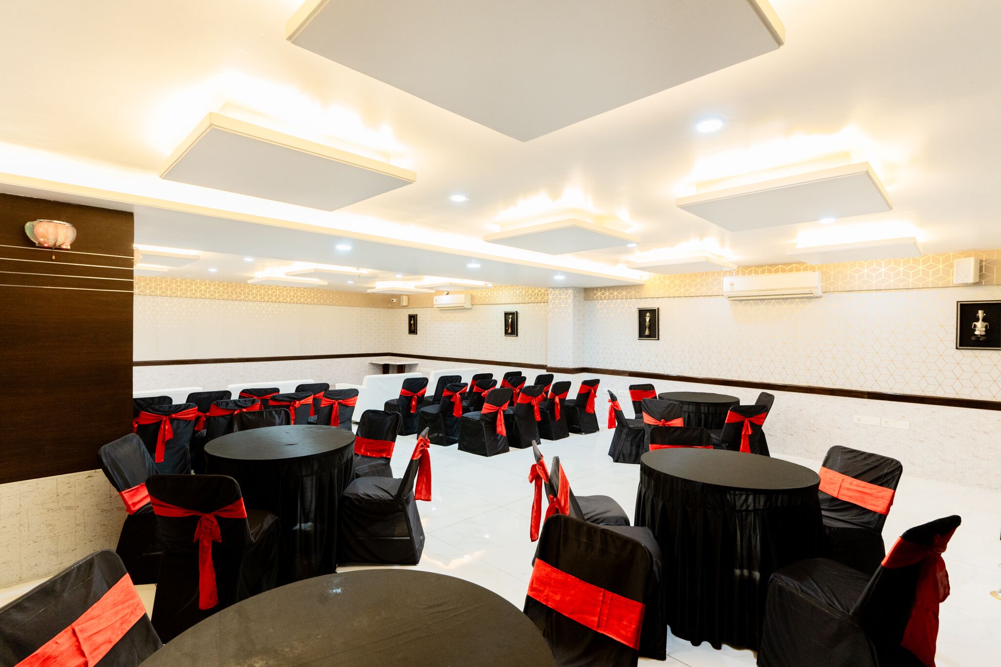 Une salle de conférence avec des rangées de tables et de chaises, chacune dotée de chaises noires et de rubans rouges.
