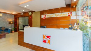 A hotel reception desk with a modern design, a clock, and a sign for Hotel Krishna. - Hotel Krishna by KeyMagics (Jaipur)