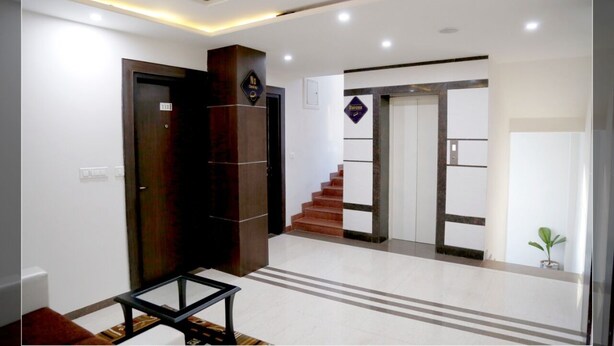 A modern hotel lobby with a staircase, a reception desk, and a small plant. - Hotel Krishna by KeyMagics (Jaipur)