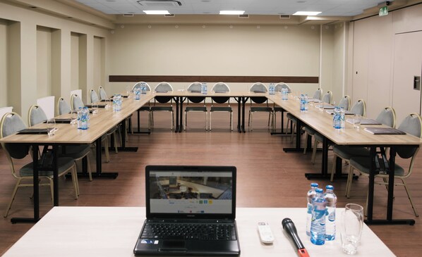 A conference room with a long table, chairs, laptops, water bottles, and a remote control. - Focus Hotel Premium Elbląg (Elblag)