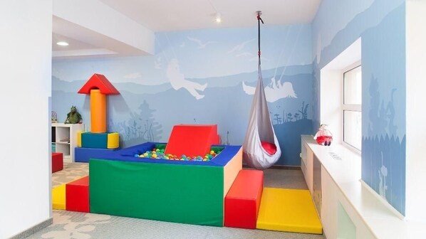 A children's play area with a ball pit, colorful play structures, and a hanging swing.