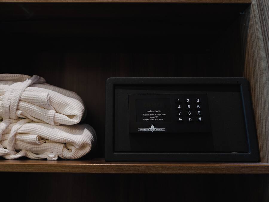 Estante de madeira com pilhas de robes brancos e um dispositivo eletrônico preto com teclado.