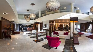 A spacious hotel lobby with a check-in counter, seating area, and a bar/lounge. - Focus Hotel Premium Elbląg (Elblag)