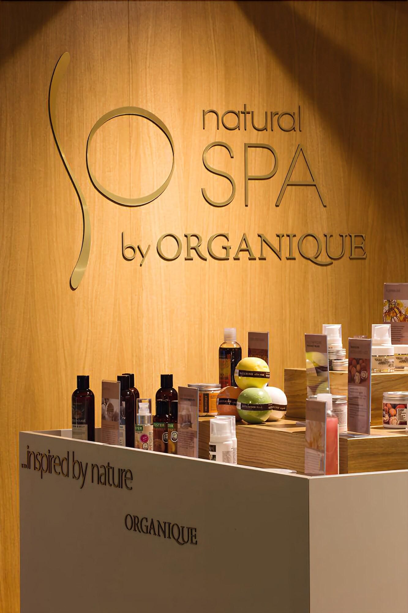 A spa area with a wooden wall and a sign that reads 'natural SPA by ORGANIQUE.' There are various spa products displayed on shelves.