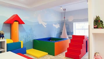 A playroom with colorful play structures, a climbing wall, and a window.