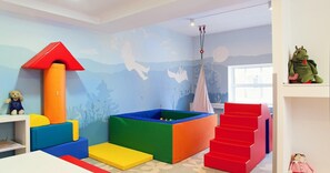 A playroom with colorful play structures, a climbing wall, and a window. - Focus Hotel Premium Elbląg (Elblag)